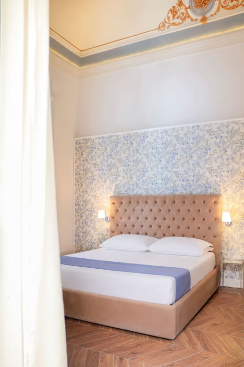 King Deluxe bedroom at Casa Beretti in Catania with tufted headboard, floral wallpaper, and elegant ceiling details
