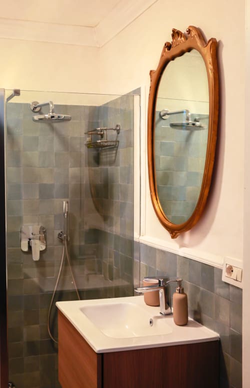 Modern bathroom at Casa Beretti King Deluxe room in Catania with wooden mirror, glass shower, and white sink.
