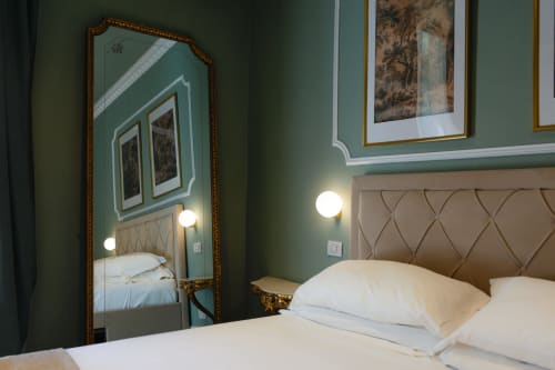 Camera deluxe di Casa Beretti a Catania con pareti verdi, testiera trapuntata, specchio ornato e applique moderne