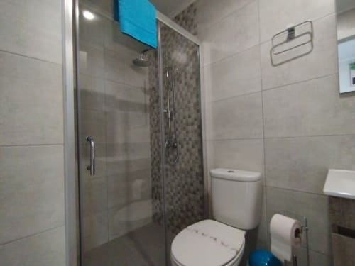 Modernes Badezimmer mit gläserner Duschkabine, Toilette und gefliesten Wänden im Furnaka Village Hostel in Lourinhã, Portugal