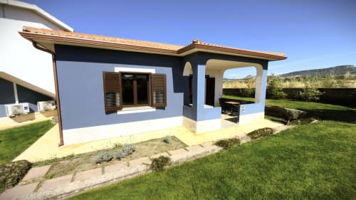 Villa Villetta 2 di A Mare Case Vacanze a Valledoria con facciata blu e bianca, persiane in legno, patio e vista sul giardino