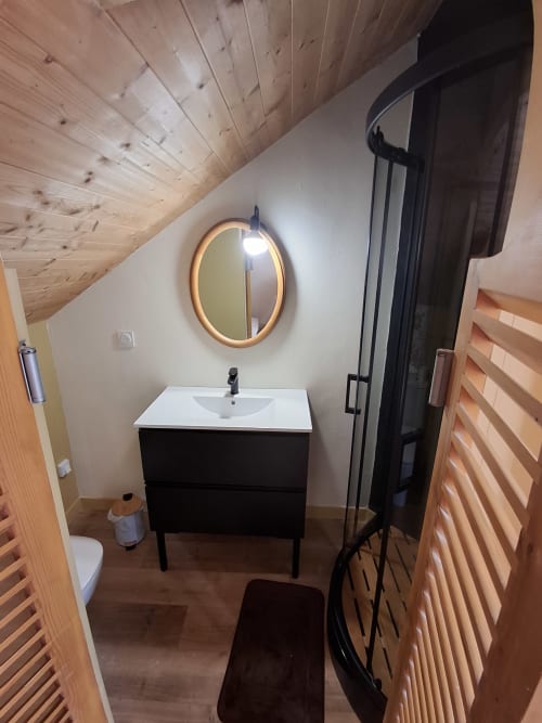 Modern bathroom in Chambre Passiflore at La Maison de Dun B&B with illuminated mirror, black vanity, and wooden accents