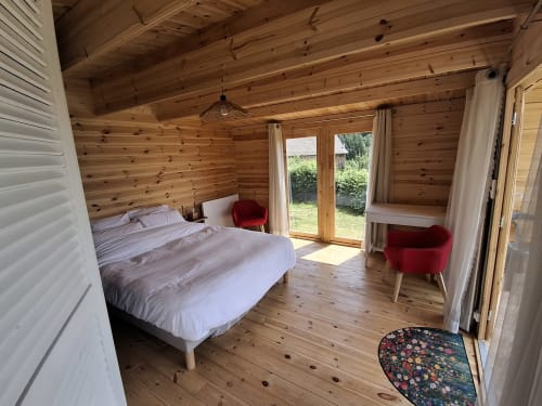 Le Grand Chêne bedroom at La Maison de Dun in Saint Racho with wooden interior, bed, red chairs, and garden view