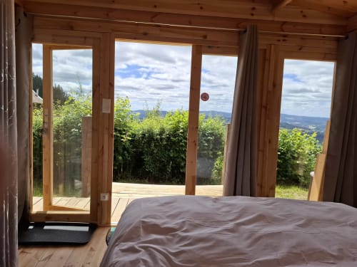 Chambre Douglas à La Maison de Dun avec portes-fenêtres en bois ouvrant sur les montagnes près de Saint Racho, France