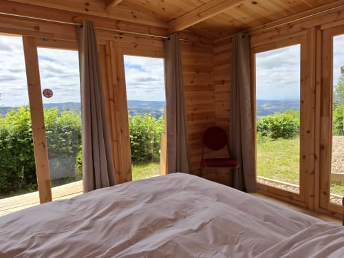 Chambre en bois avec vue panoramique sur les montagnes par les grandes fenêtres de La Maison de Dun, Saint Racho