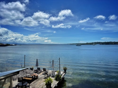Oceanfront deck at BarrBra BnB in Bocas del Toro with loungers, umbrella, and sailboats on turquoise water