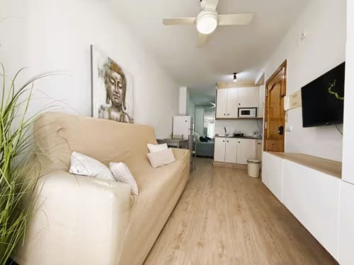 Acogedor estudio en primera línea de playa en Fuengirola con sofá crema, kitchenette, TV y comodidades modernas