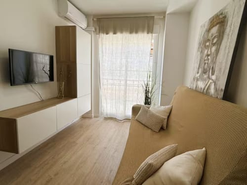 Acogedor estudio frente al mar en Fuengirola con mobiliario moderno, sofá, TV y balcón con vistas al mar