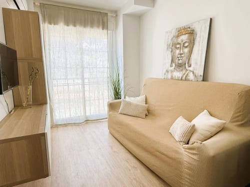 Acogedor estudio frente al mar en Fuengirola con sofá beige, muebles de madera y decoración moderna