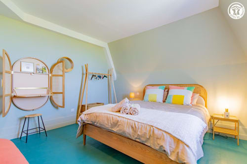 Chambre lumineuse à Ô 3 Cyprès de Précy avec lit en bois, coussins colorés, sol turquoise et miroirs en rotin à Neuvy