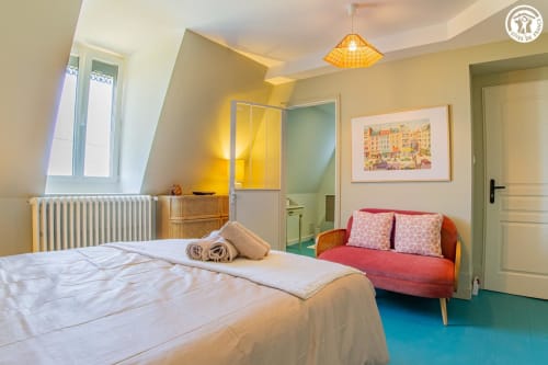 Chambre lumineuse à Ô 3 Cyprès de Précy B&B à Neuvy Grandchamp avec lit, canapé rouge, touches jaunes et vue sur le jardin