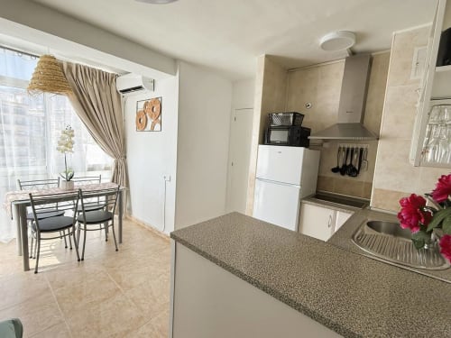 Cocina y comedor modernos en luminoso apartamento frente al mar en Fuengirola, con encimeras de granito y electrodomésticos blancos