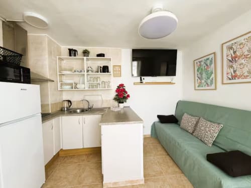 Moderno apartamento soleado en Fuengirola con cocina abierta, sofá verde y decoración contemporánea