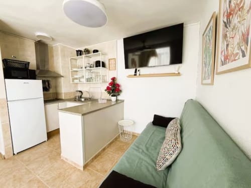 Luminoso apartamento frente al mar en Fuengirola con cocina abierta, sala de estar, TV y sofá verde