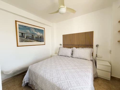 Dormitorio soleado en apartamento céntrico frente a playa, Fuengirola, con cabecero de madera y ventilador de techo moderno