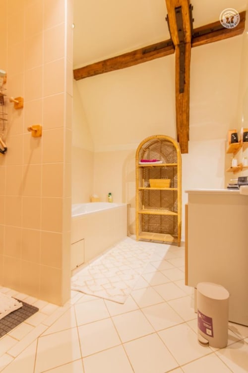 Salle de bain du gîte Ô 3 Cyprès de Précy à Neuvy Grandchamp : baignoire, étagères tressées et carrelage