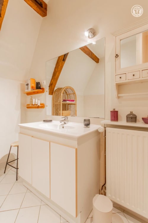 Salle de bain moderne à Ô 3 Cyprès de Précy : vasque blanche, grand miroir, poutres en bois et étagères orange, chambre Charlemagne