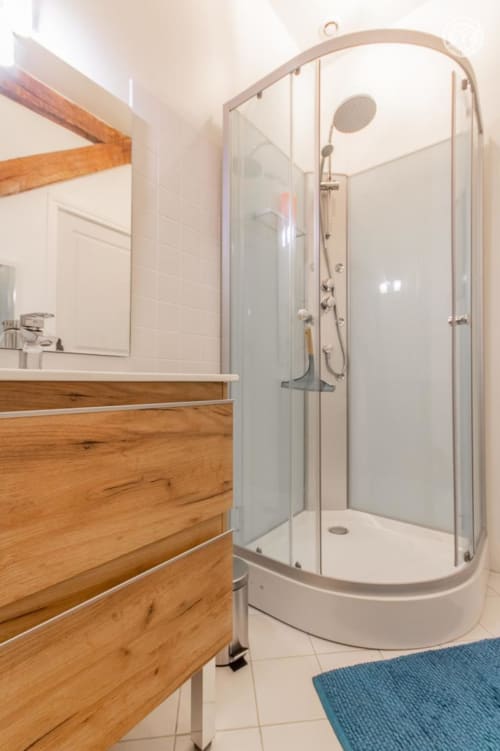 Salle de bain moderne à Ô 3 Cyprès de Précy avec meuble-lavabo en bois, douche vitrée et carrelage blanc