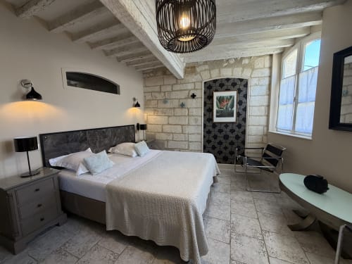 Modernes Schlafzimmer im Hôtel La Suite mit Steinmauern, weißer Kassettendecke, dunklem Bett und Stadtblick in Villeneuve-lès-Avignon