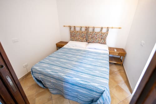 Camera da letto accogliente nell'appartamento Emily in Sicily a San Vito Lo Capo con biancheria blu a righe, comodini in legno e motivi decorativi