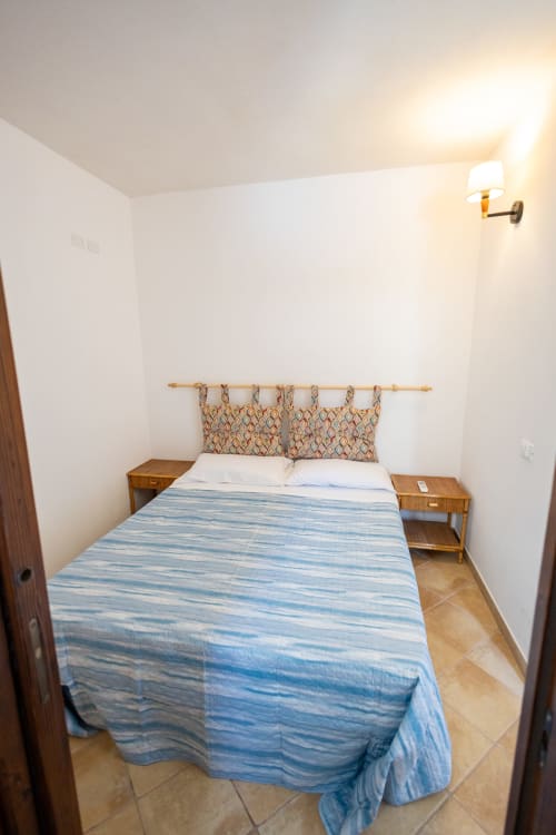Accogliente camera da letto nell'appartamento Emily in Sicily a San Vito Lo Capo con biancheria blu a righe e comodini in legno