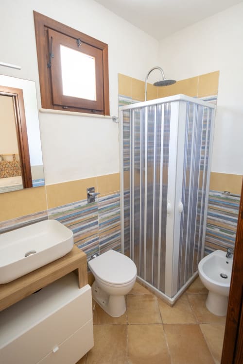 Bagno moderno nell'appartamento Emily in Sicily, San Vito Lo Capo con piastrelle bianche, dettagli rigati e box doccia
