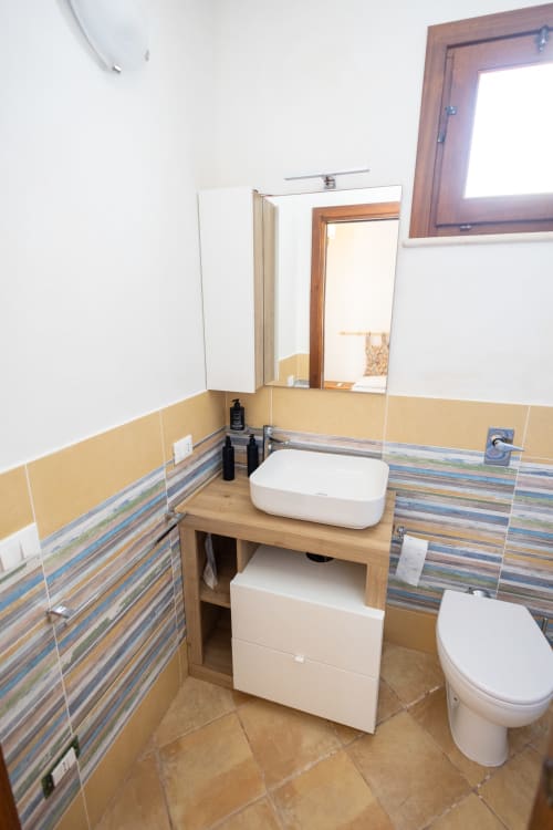 Bagno moderno nell'appartamento Emily in Sicily a San Vito Lo Capo, con lavabo vessel, piastrelle righe e wc