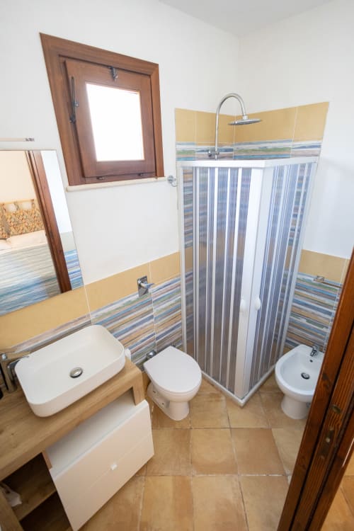 Bagno moderno nell'appartamento di Emily, San Vito Lo Capo Sicilia con doccia, wc, lavandino e piastrelle gialle