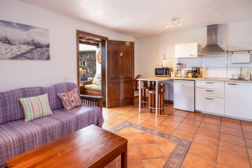 Apartamento diáfano en Villanueva Lanzarote con sofá morado, cocina, baldosas de terracota y vistas a las montañas en Mala, España