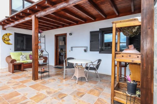 Amplia terraza con pérgola de madera, mesa de comedor, asientos y vistas a la montaña en apartamento Villanueva Lanzarote en Mala