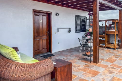 Terraza del patio de apartamento Villanueva Lanzarote con asientos de mimbre, muebles de madera, suelo de baldosa y vistas a la montaña