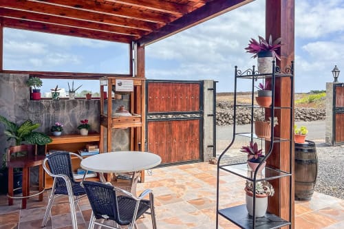 Terraza exterior de Villanueva Lanzarote con mesa de comedor, sillas, plantas en macetas y vistas a las montañas de Mala