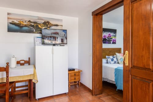 Sala de estar del apartamento en Villanueva Lanzarote con muebles de madera, refrigerador blanco y puerta hacia el dormitorio