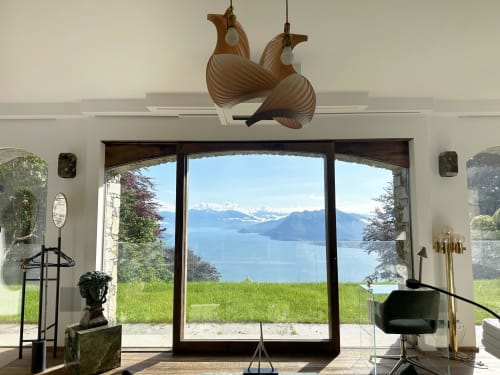 Luxury spa retreat studio with expansive lake view of Lake Maggiore, modern wood chandelier, and panoramic terrace doors