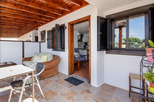 Terraza del apartamento Villanueva Lanzarote con asientos de mimbre, vigas de madera, vistas al jardín y macetas