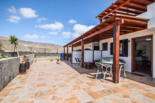 Terraza espaciosa con pérgola de madera, vistas panorámicas del jardín y zona de descanso en Villanueva Lanzarote, Mala