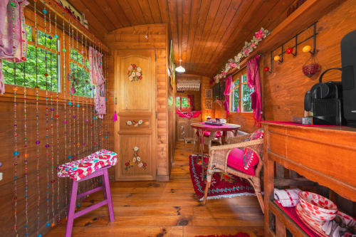 Chambre colorée de roulotte en bois aux Gîtes du Rouard à Camiers, avec rideaux à perles, décoration rose et vue sur le jardin