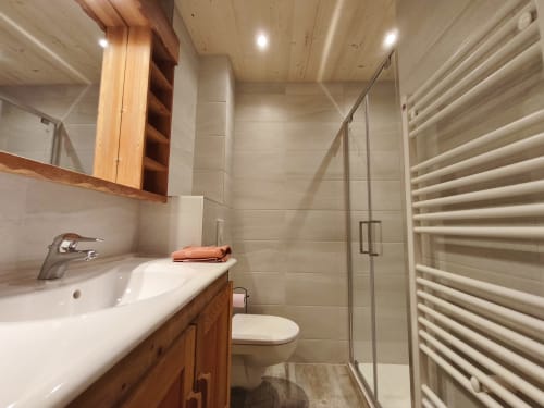 Salle de bains moderne avec meuble vasque en bois, douche et sèche-serviettes chauffant au Chalet Coste Belle, Ceillac