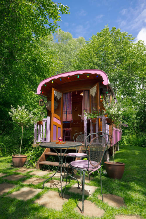 Roulotte bohème colorée aux toits roses aux Gîtes du Rouard à Camiers, entourée de verdure luxuriante