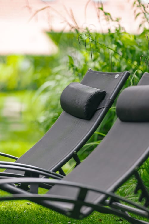 Chaises longues noires avec coussins sur la pelouse du jardin aux Gîtes du Rouard, Camiers