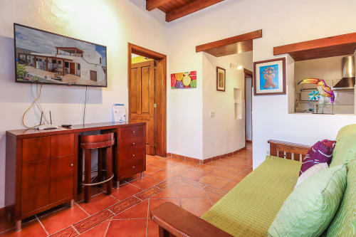 Dormitorio moderno en Villanueva Lanzarote con suelos de barro, muebles de madera, televisión y vistas al jardín en Mala