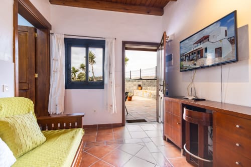 Luminoso salón con vistas a la terraza en Villanueva Lanzarote, con muebles de madera, TV y acceso al jardín