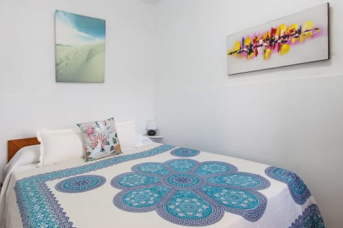 Dormitorio en Villanueva Lanzarote con ropa de cama turquesa estampada, almohadas blancas y dos obras de arte en paredes blancas