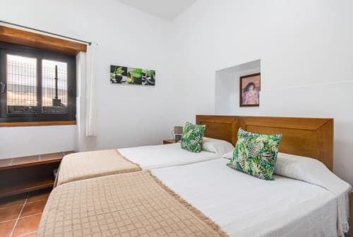 Dos camas individuales con cojines verdes en dormitorio luminoso del apartamento Villanueva Lanzarote, Malá