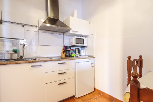 Cocina moderna en apartamento de Villanueva Lanzarote con armarios blancos, campana acero inoxidable, microondas y azulejos terracota