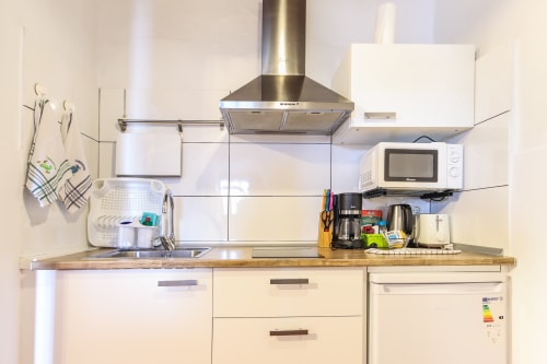 Cocina moderna en apartamento de Villanueva, Lanzarote con armarios blancos, electrodomésticos de acero inoxidable y encimera de madera.