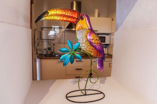 Colorida escultura decorativa de tucán con flor turquesa en apartamento de Villanueva Lanzarote, decoración con vista al jardín