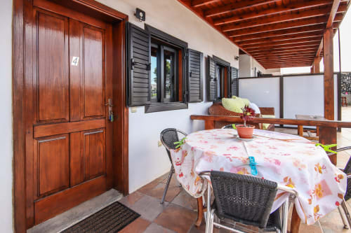 Terraza cubierta en Villanueva Lanzarote con puertas de madera, mesa de comedor y vistas al jardín de montaña