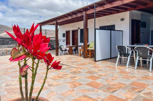 Terraza en Villanueva Lanzarote con flores rojas, vista al jardín, zona de comedor y vistas a la montaña en Mala