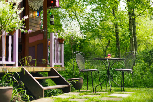 Coin salon du jardin aux Gîtes du Rouard à Camiers avec chaises bistrot en métal, table et feuillage verdoyant